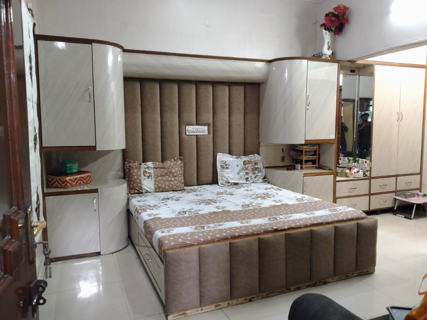Upholstered bed with channel-tufted headboard and flanking curved-corner wardrobes
